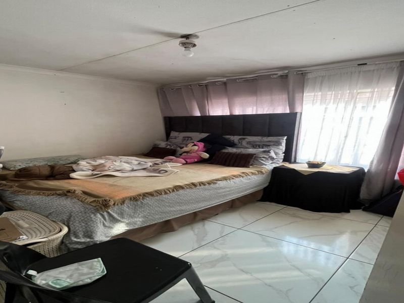 A bedroom featuring tiled flooring and curtain rails, requiring minor cosmetic updates to the walls and ceiling to enhance its overall appeal.