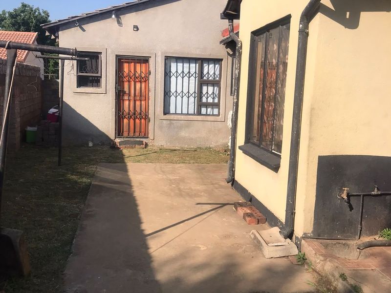 Rear exterior view of the property featuring a concrete patio area, security gates on doors and windows, and established exterior wall finishes.