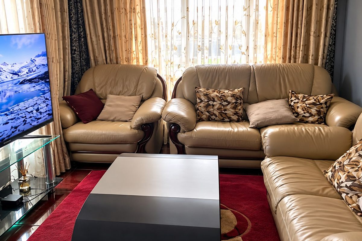 A comfortable living room featuring tiled flooring and large window treatments, providing a functional space for relaxation.