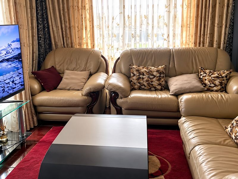 A comfortable living room featuring tiled flooring and large window treatments, providing a functional space for relaxation.