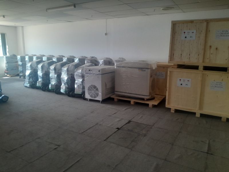 Industrial utility space featuring a suspended ceiling and worn flooring, currently utilized for storage of equipment and shipping crates.