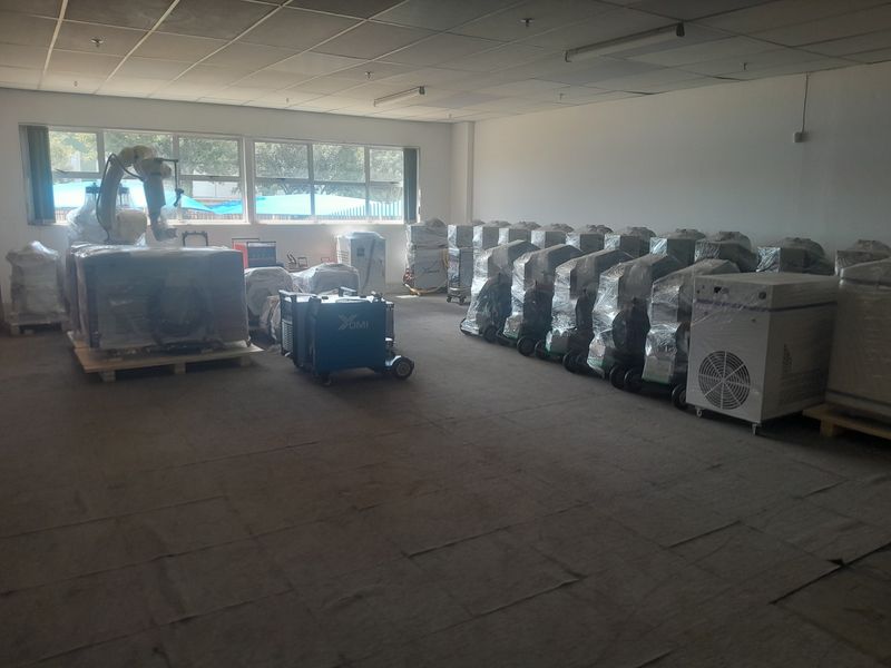 Spacious industrial utility area featuring a suspended ceiling, fluorescent lighting, and large windows, currently utilized for equipment storage.