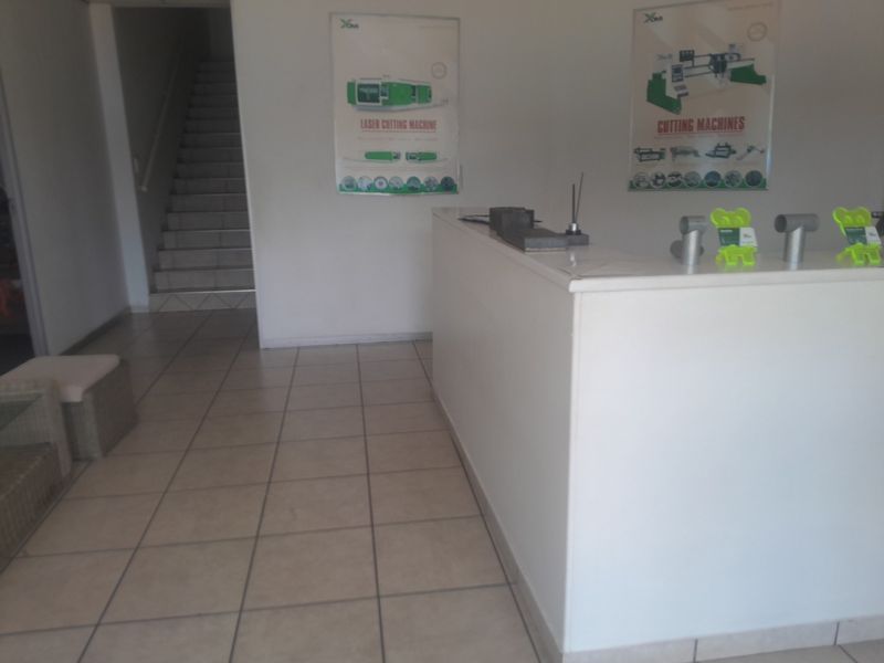 Industrial reception area featuring a built-in service counter, tiled flooring, and access to an internal staircase.