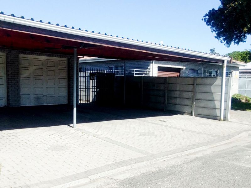 A paved driveway featuring a covered carport structure and a secure garage door, providing convenient off-street parking for the property.