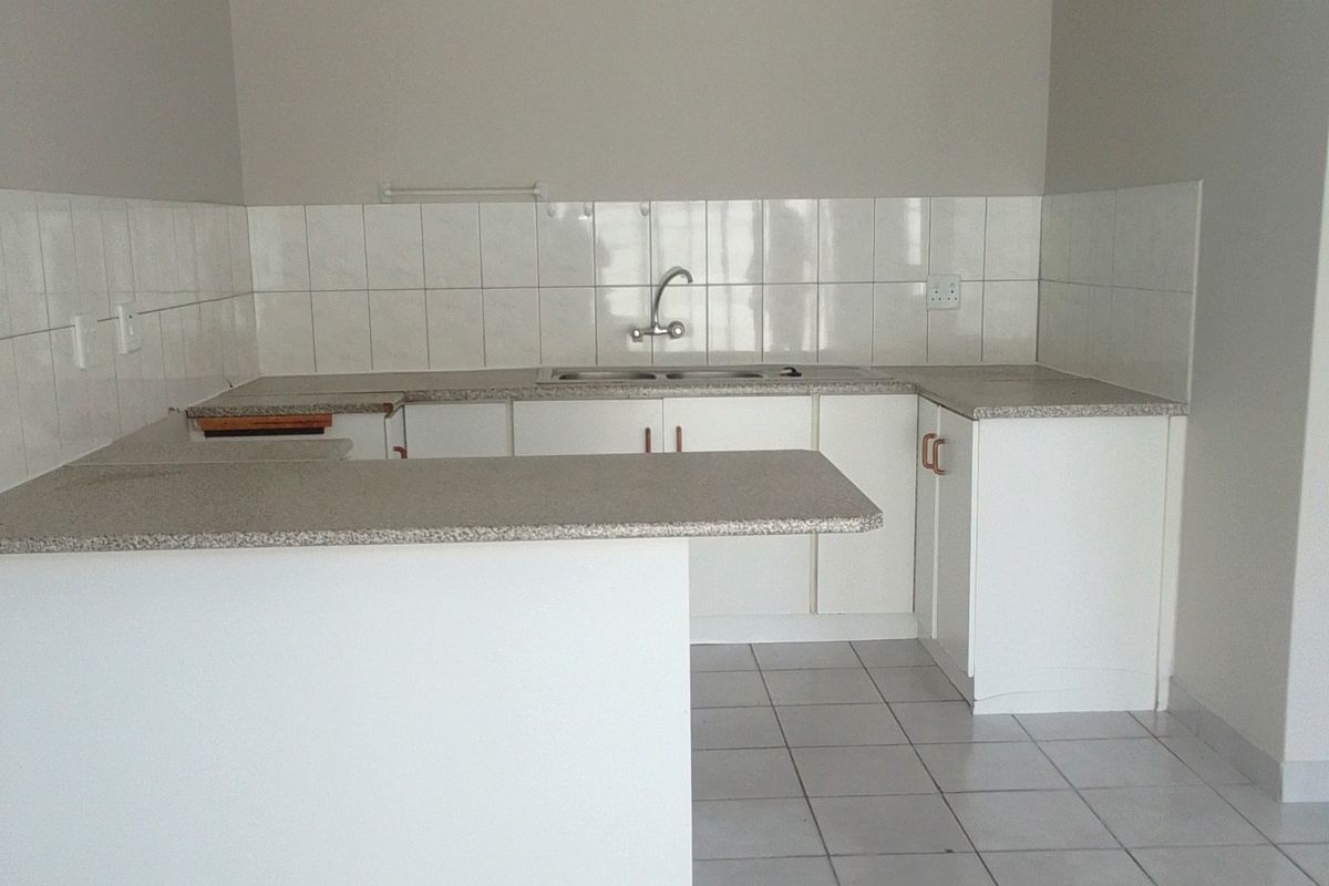 A clean, functional kitchen featuring white cabinetry, granite countertops, a breakfast nook, and tiled flooring, offering a neutral canvas for potential updates.
