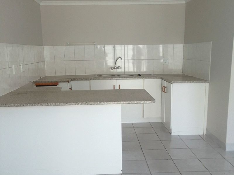 A clean, functional kitchen featuring white cabinetry, granite countertops, a breakfast nook, and tiled flooring, offering a neutral canvas for potential updates.