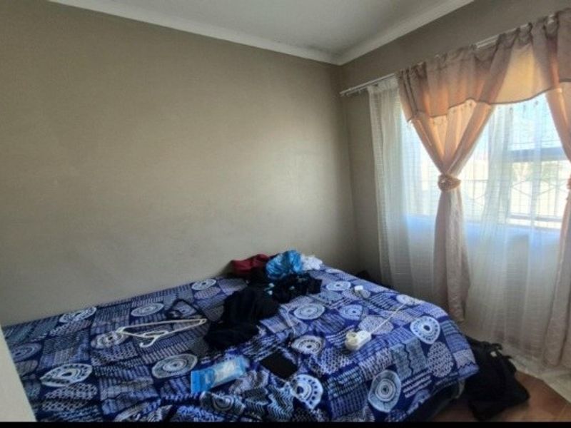 A standard bedroom featuring neutral wall paint, coving, and a window with installed curtain rods.