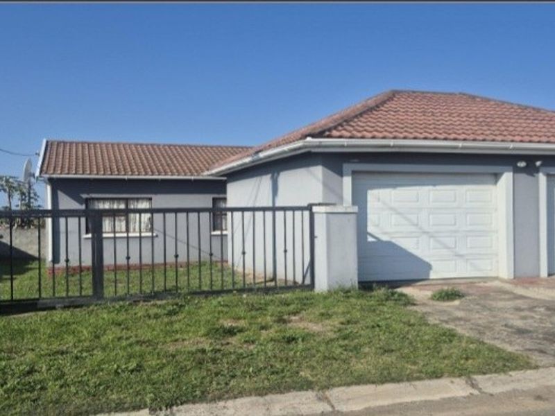 Front exterior view of a single-story house featuring a double garage, tiled roof, and a metal security gate with a concrete driveway.
