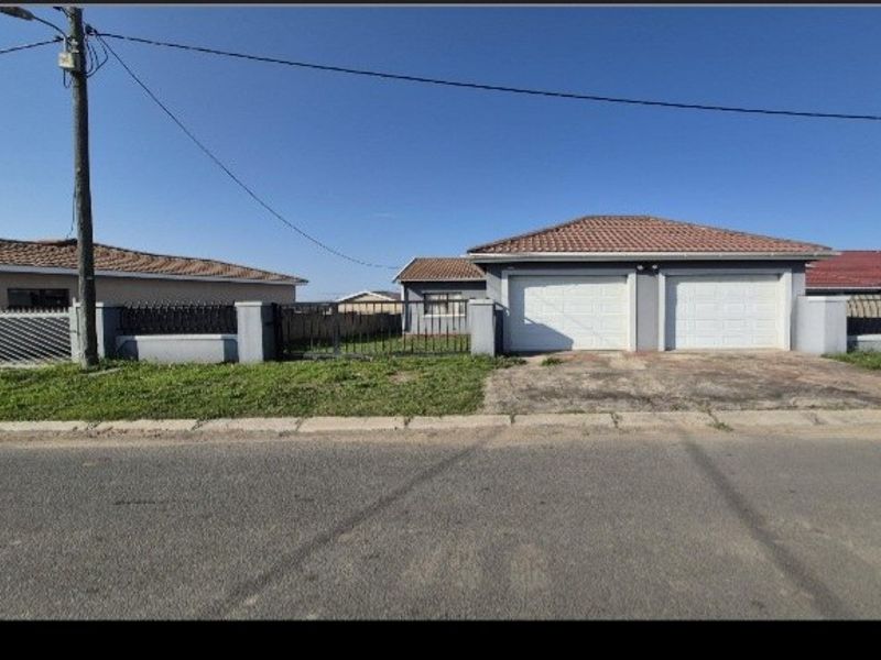 Front view of a residential property featuring a double garage, tiled roof, and perimeter boundary wall with gated access.