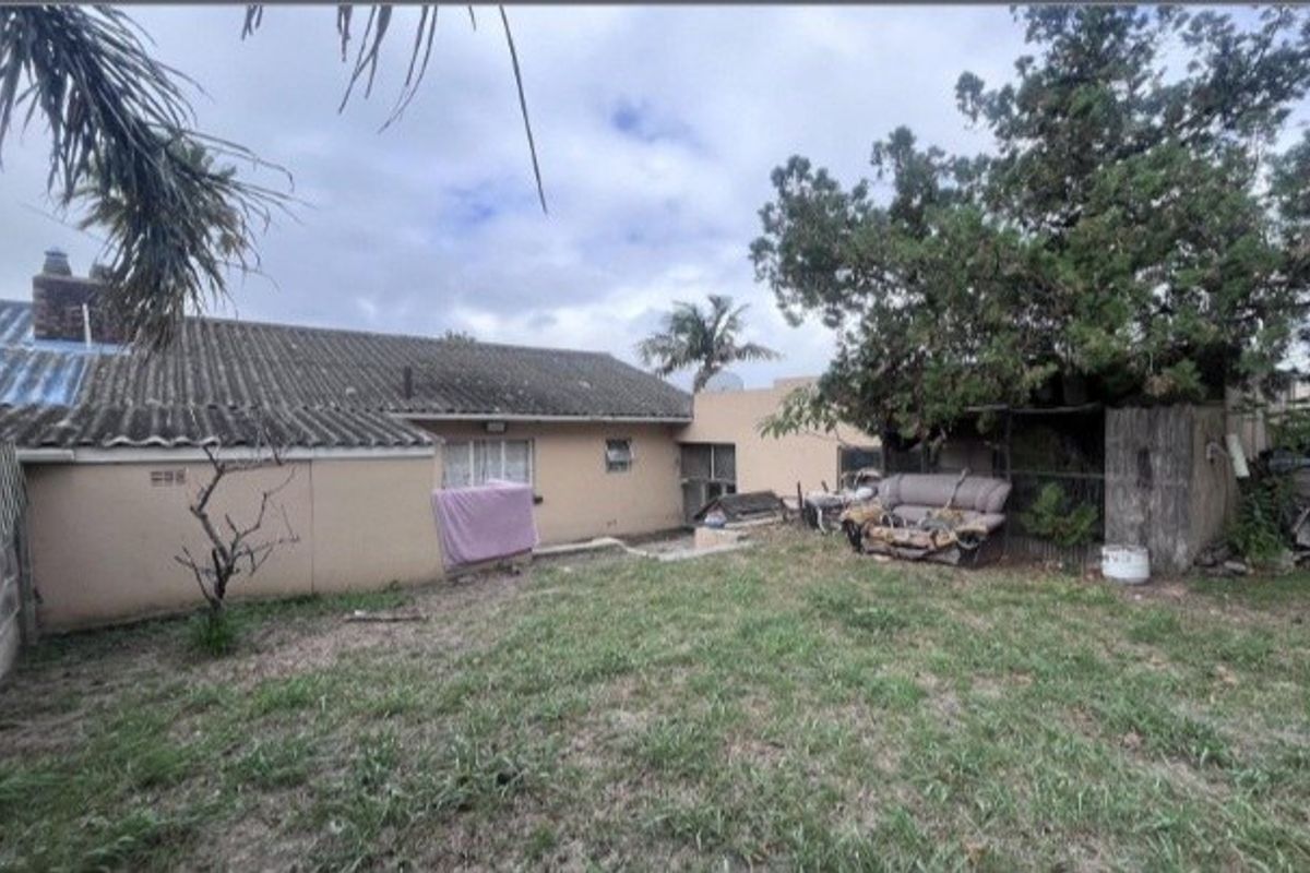 Rear view of the property showing the back facade, tiled roof, and garden area with mature trees.