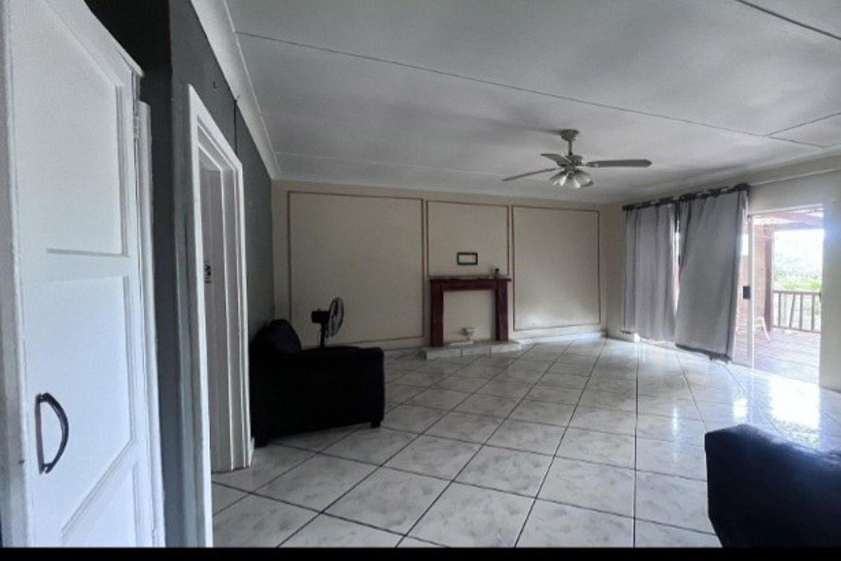 Spacious living room featuring tiled flooring, a central fireplace, ceiling fan, and sliding glass doors leading to an outdoor area.