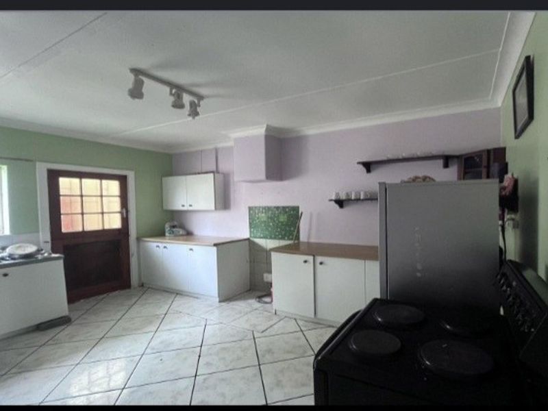 A dated kitchen featuring tiled flooring, built-in cabinetry, and laminate countertops, offering potential for a modern renovation to enhance functionality and aesthetic appeal.