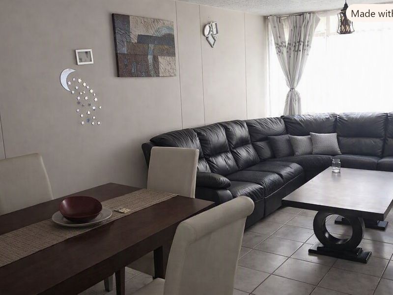 An open-plan living and dining area featuring tiled flooring and a large window, providing a functional and versatile space for daily living.