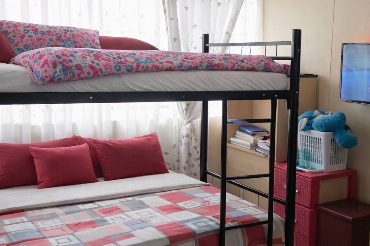 A bedroom featuring tiled flooring and a popcorn ceiling, currently furnished with a bunk bed.
