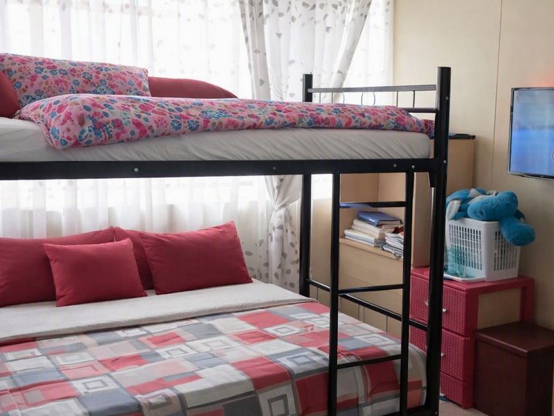 A bedroom featuring tiled flooring and a popcorn ceiling, currently furnished with a bunk bed.