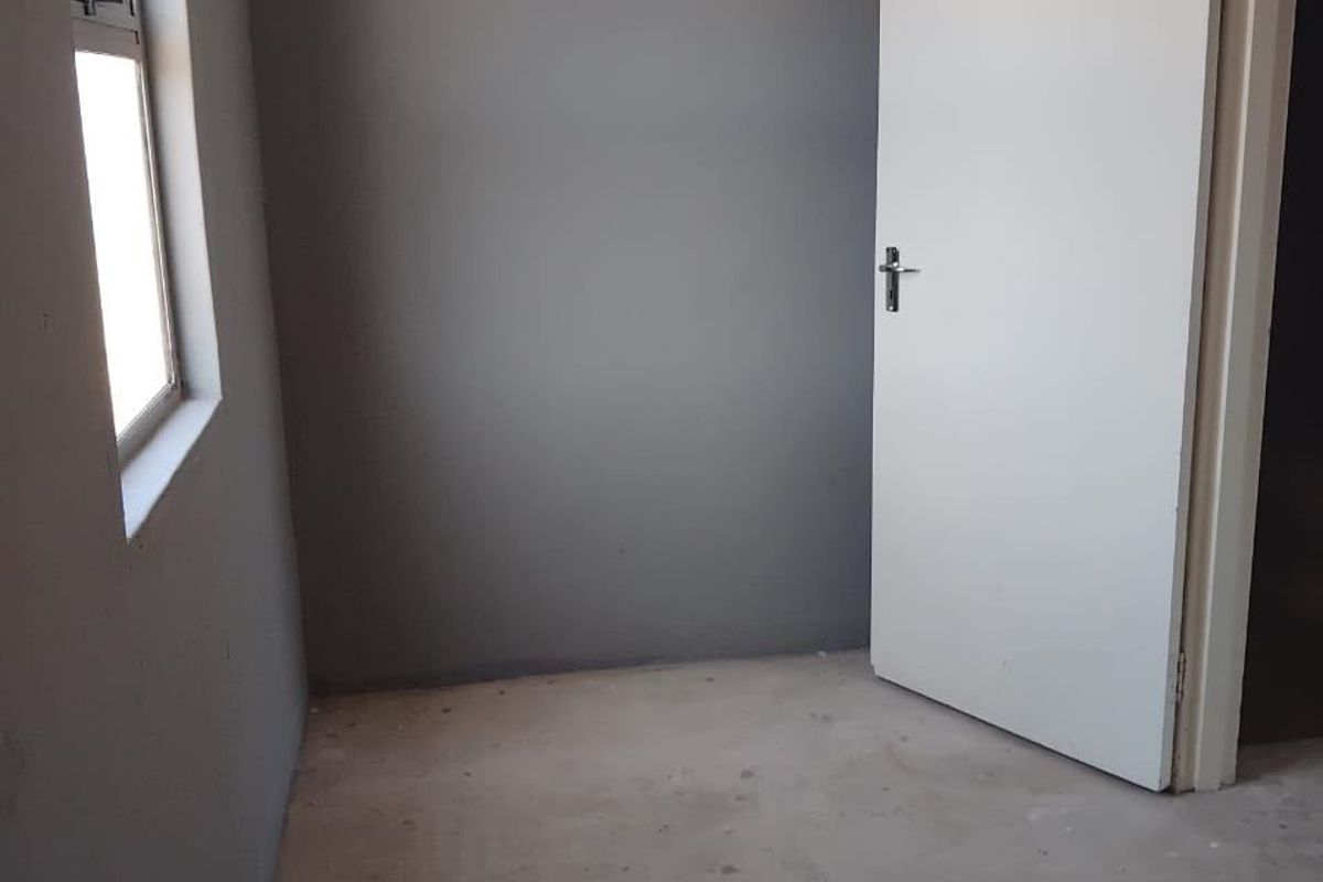 An empty bedroom featuring grey painted walls, an internal door, and an unfinished concrete floor, awaiting final flooring installation.