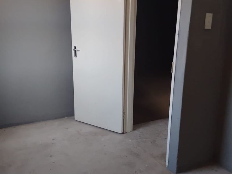 An empty bedroom featuring grey painted walls and unfinished concrete flooring, awaiting final flooring installation and finishing touches.