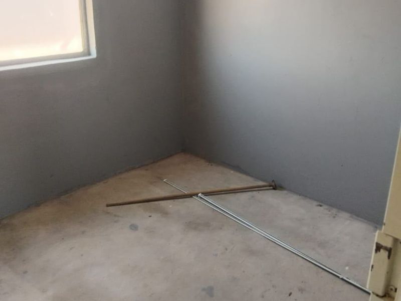 An empty, unfinished bedroom featuring bare concrete flooring and grey painted walls, offering a blank canvas for renovation and interior design.