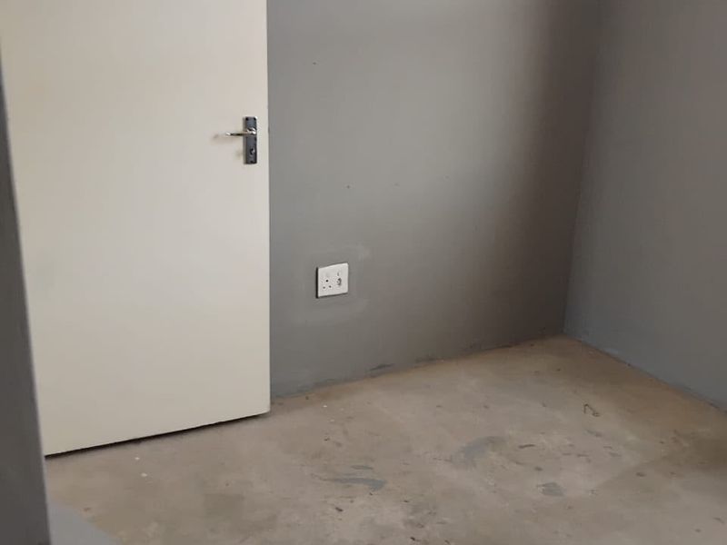 An empty bedroom featuring grey painted walls and an unfinished concrete floor, ready for final flooring installation and finishing touches.