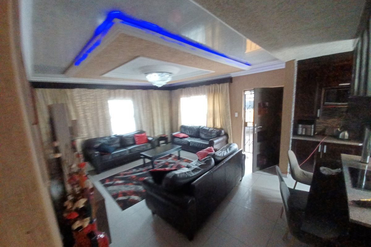 Open-plan living and kitchen area featuring a modern recessed ceiling with blue accent lighting and tiled flooring throughout.
