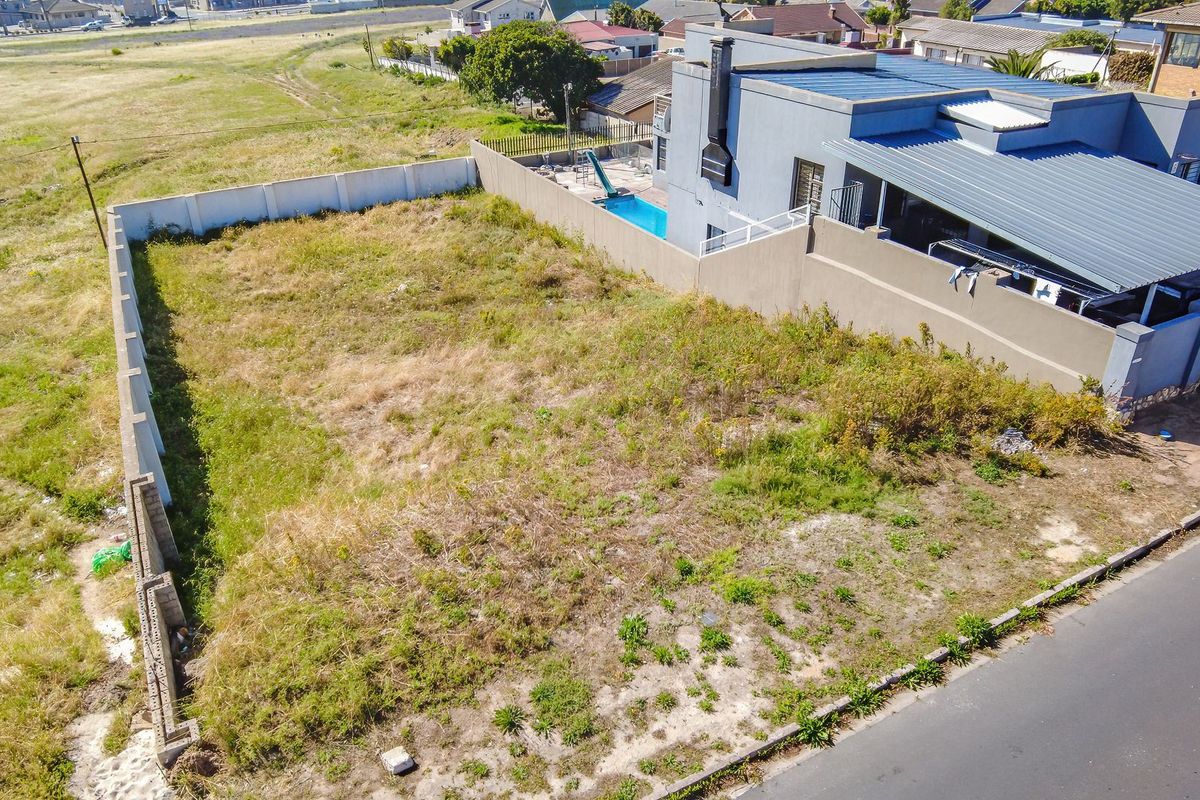 Aerial view of a vacant residential plot featuring perimeter boundary walls and direct road access, situated in an established neighborhood.