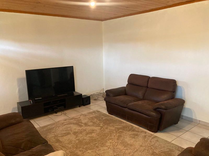 A living room featuring tiled flooring and a timber ceiling, providing a neutral base for interior design updates.