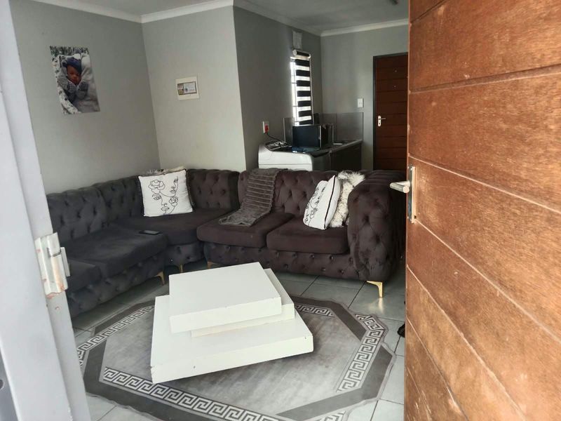 Open plan living area featuring tiled flooring and a compact kitchen corner, providing a functional and connected layout for daily living.