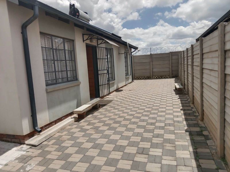A paved rear courtyard featuring a precast concrete boundary wall with security razor wire and a solar water heater installed on the roof.