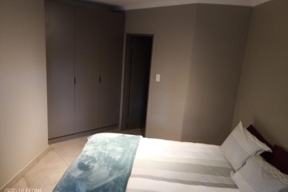 A bedroom featuring neutral wall tones, tiled flooring, and built-in cupboards providing ample storage space.