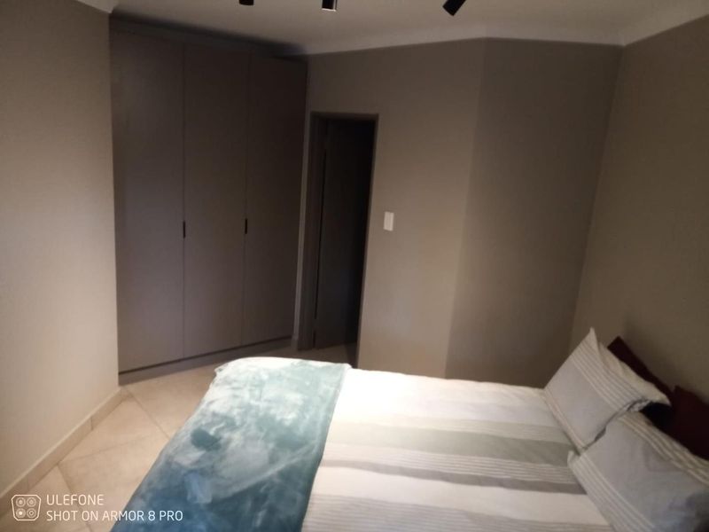 A bedroom featuring neutral wall tones, tiled flooring, and built-in cupboards providing ample storage space.