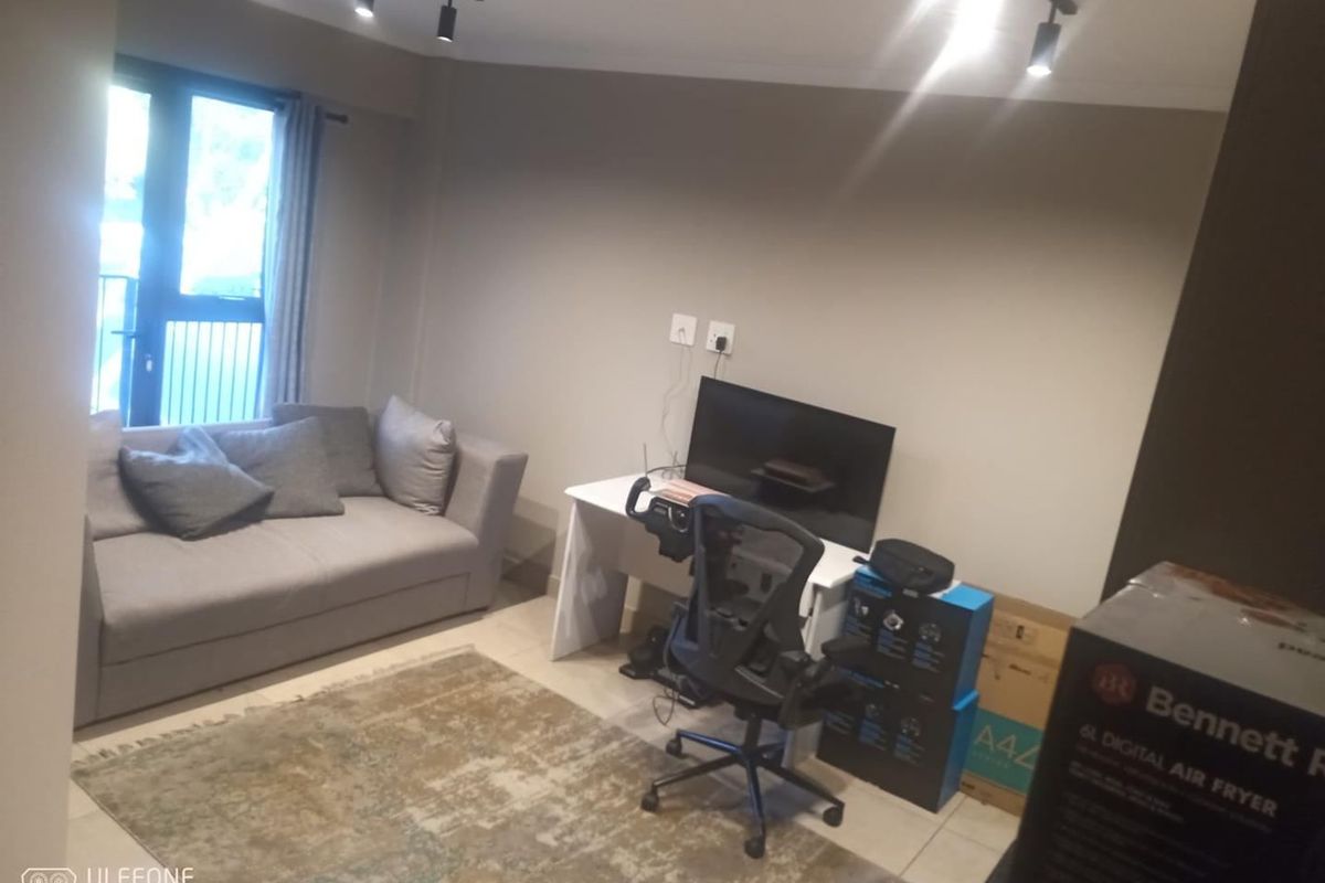 A living room area featuring tiled flooring, track lighting, and a sliding door leading to a balcony.