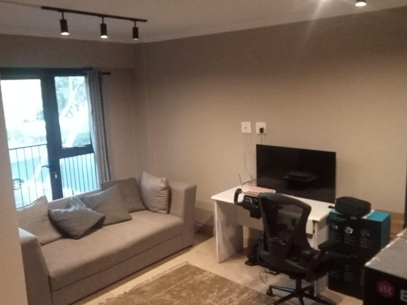 A living room area featuring track lighting and a double glass door providing access to a balcony.