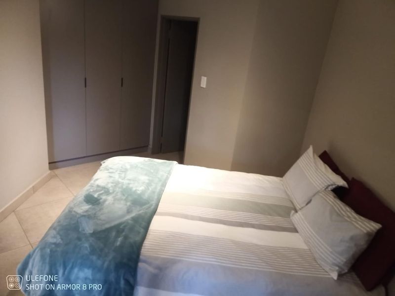 A bedroom featuring built-in cupboards and tiled flooring, providing a functional and neutral living space.