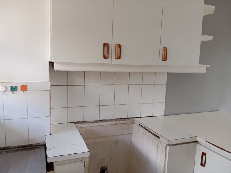 A dated kitchen area featuring white built-in cabinetry, tiled backsplash, and a dedicated space for a stove or appliance.
