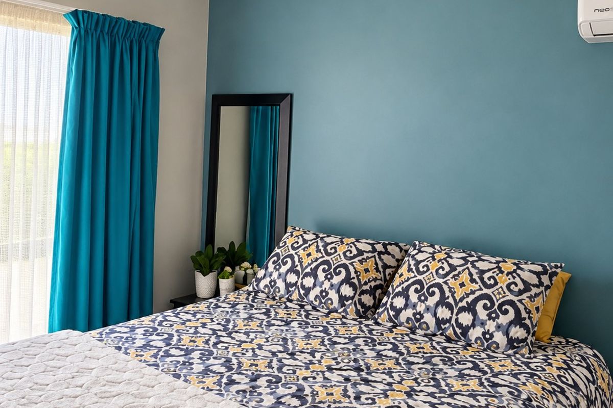 A well-maintained bedroom featuring a ceiling fan, split-system air conditioning unit, and decorative coving.