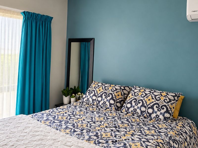 A well-maintained bedroom featuring a ceiling fan, split-system air conditioning unit, and decorative coving.