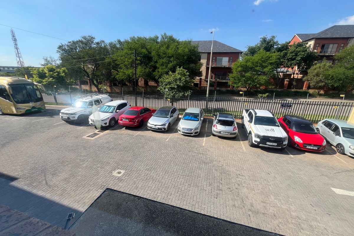 An elevated view of a paved industrial parking area featuring perimeter security fencing and multiple parking bays.