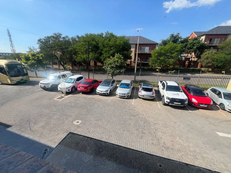 An elevated view of a paved industrial parking area featuring perimeter security fencing and multiple parking bays.