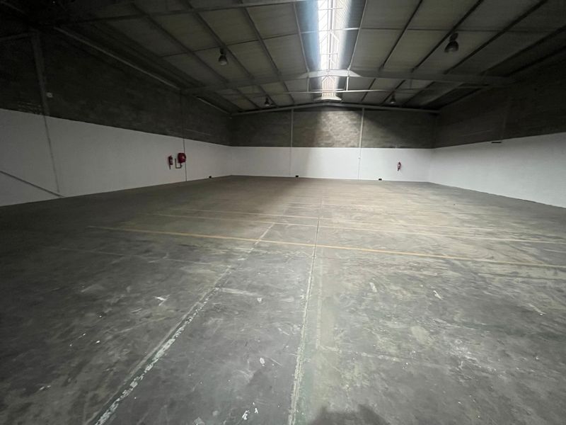Spacious industrial warehouse unit featuring high ceilings with skylights, durable concrete flooring, and exposed steel structural elements, suitable for storage or manufacturing operations.