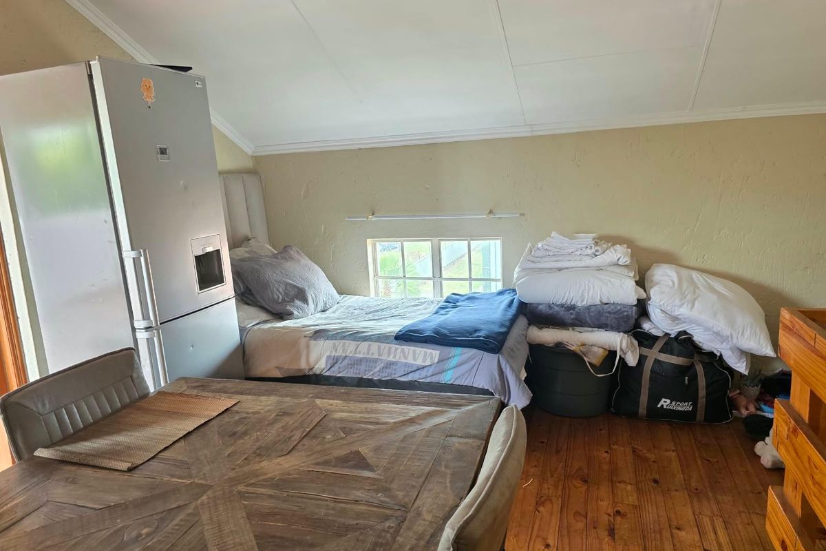 A bedroom space featuring timber flooring and a pitched ceiling with a small casement window, requiring cosmetic updates to the wall finishes.