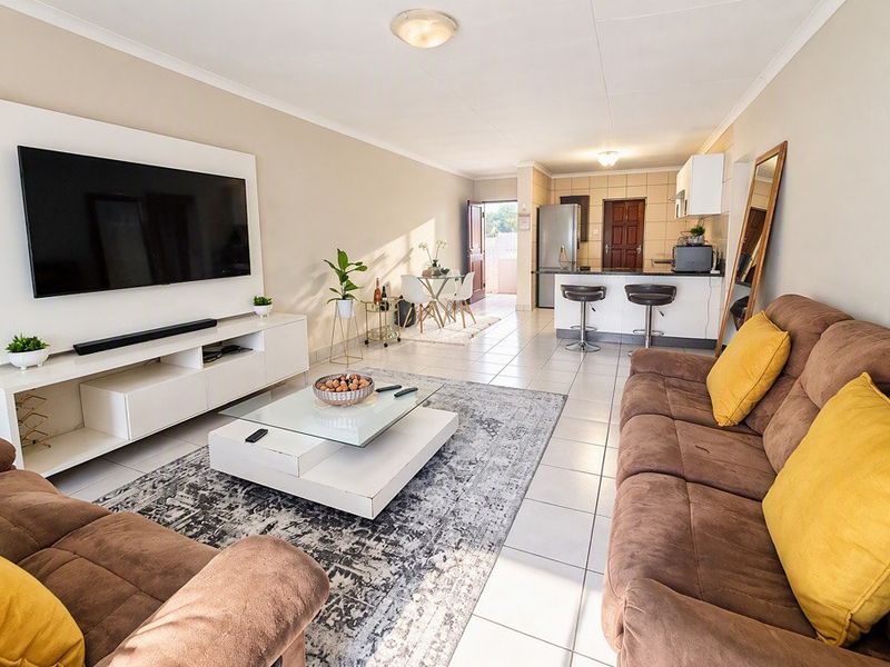 Spacious open-plan living area featuring tiled flooring and a modern kitchen with a breakfast bar, seamlessly connecting to the lounge space.