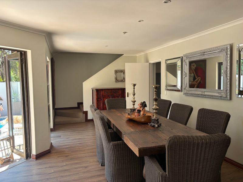 A spacious dining room featuring laminate flooring, recessed lighting, and direct access to an outdoor area through double glass doors.