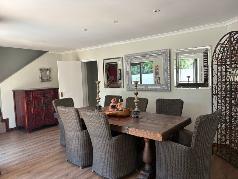 A well-maintained dining room featuring laminate flooring and recessed downlighting, providing a functional and inviting space for meals.