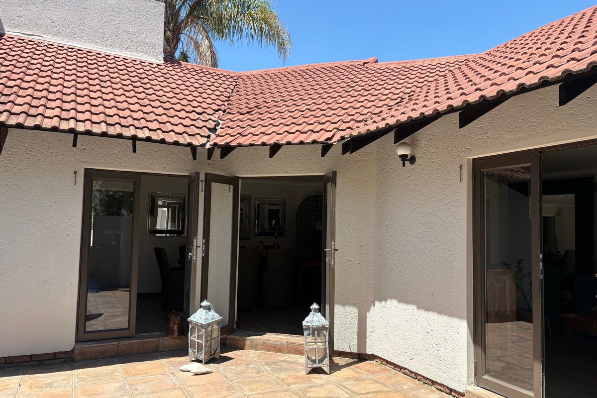 A rear patio area featuring terracotta roof tiles, textured walls, and multiple aluminium-framed glass doors providing access to the interior living spaces.