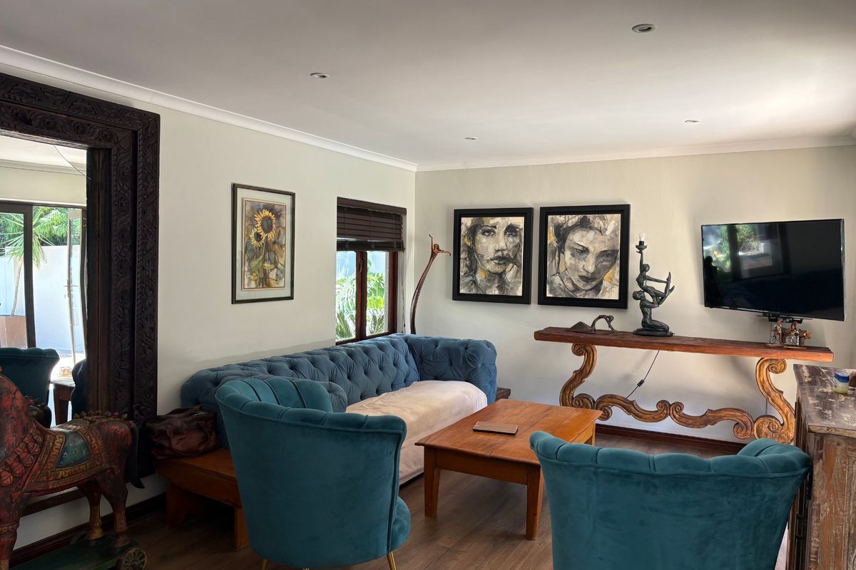 A well-maintained living room featuring laminate flooring, recessed downlighting, and wooden window frames, creating a comfortable and inviting atmosphere.