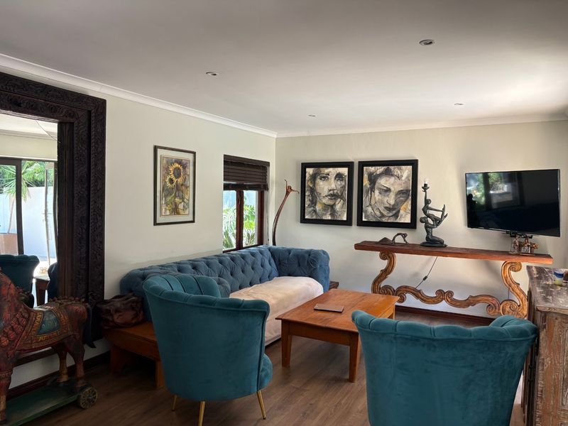 A well-maintained living room featuring laminate flooring, recessed downlighting, and wooden window frames, creating a comfortable and inviting atmosphere.