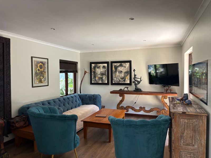 A comfortable living room featuring laminate flooring, recessed downlighting, and coved cornicing, creating a warm and inviting atmosphere.