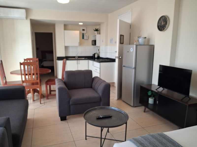 Open plan living area featuring a functional kitchen with built-in cabinetry and tiled flooring throughout.