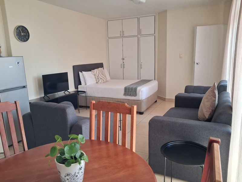 Open-plan living and sleeping area featuring tiled flooring and built-in storage cupboards.