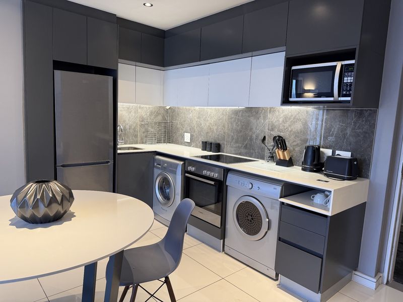 Modern kitchen featuring sleek two-tone cabinetry, stone countertops, integrated appliances, and a stylish stone splashback, offering a clean and contemporary aesthetic.